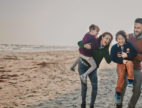 Un couple avec deux enfants rient lors d'une ballade sur la plage